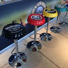 four stools with different colored seats in front of a large advertisement wall behind them