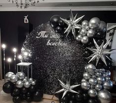 black and silver balloon decorations in front of a large rock with stars on the top