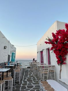 an outdoor dining area with tables and chairs next to the ocean