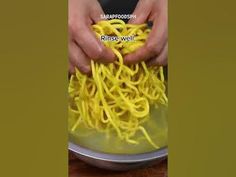 two hands are sprinkling yellow noodles on a plate