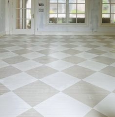 an empty room with two windows and a checkered floor in front of the door