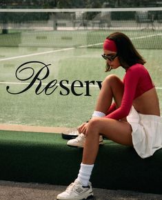 a woman sitting on a bench in front of a tennis court with the words reserved behind her