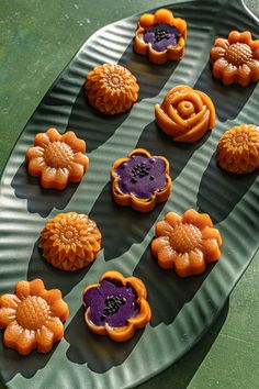 there are many cookies on the plate with purple icing and flowers in them,