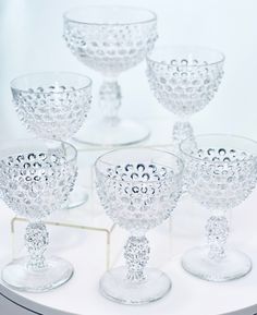 six clear goblets are sitting on a white table