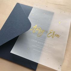 an open silver and black wedding card with gold foil lettering on the inside, sitting on top of a wooden table