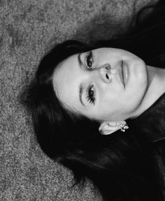 a black and white photo of a woman laying on the floor with her eyes closed