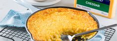 a pot pie with a spoon in it on a cooling rack next to a container of cheddar