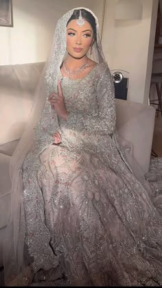 a woman sitting on top of a white couch wearing a wedding dress and holding a finger