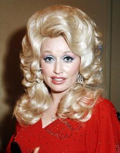 a woman with blonde hair and blue eyes posing for a photo in a red dress