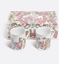 two mugs sitting next to each other on top of a tablecloth covered box