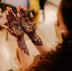 a woman holding her hands up with henna on it