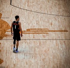 a man standing on top of a basketball court with a ball in his hand next to him