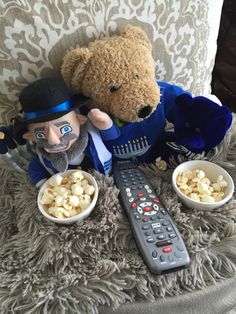 two stuffed animals are sitting on a chair with popcorn and a remote control