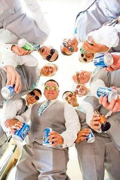 a group of men in suits and ties holding cans of sodas while standing together