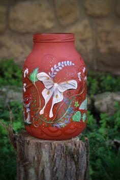 a painted jar sitting on top of a tree stump