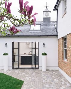 a white house with purple flowers on the front door and windows in the back yard