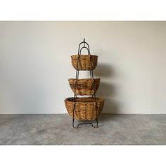 three wicker baskets stacked on top of each other in front of a white wall