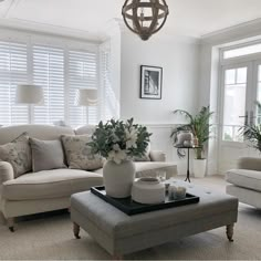 a living room with couches, chairs and a coffee table in front of two windows