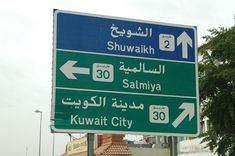 a street sign in the middle of a city with many different languages and numbers on it