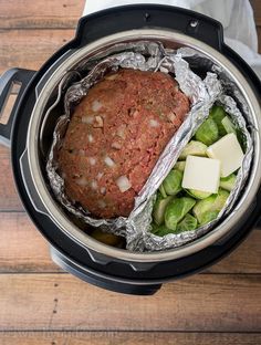 an open crock pot filled with meat and vegetables on top of a wooden table