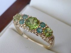 BEAUTIFUL Victorian Inspired 9CT/9K SOLID GOLD PERIDOT & EMERALD VINTAGE SCROLL RING This lovely Vintage Inspired ring has been crafted from 9ct Solid Gold. A central Natural Peridot gemstone is accentuated by two Natural Peridots and four Natural Emeralds on the face bringing this ring to life. All gemstones are prong set and a marvellous feature is that underneath the face of this GORGEOUS Peridot and Emerald ring is a gallery that has a scroll design which makes this ring more appealing t Classic Green Multi-stone Sapphire Ring, Heirloom Green Sapphire Ring, Antique Green Multi-stone Ring, Heirloom Green Multi-stone Rings, 14k Gold Green Multi-stone Cluster Ring, Heirloom 14k Gold Green Cluster Ring, Vintage Green Birthstone Ring Hallmarked, Heirloom Green Cluster Ring In 14k Gold, Heirloom Green Hallmarked Rings