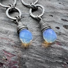 These long dangle earrings are handmade from sterling silver and Opalite. The small Opalite teardrops are wrapped in sterling silver. Above the teardops are a set of rings which I have formed, soldered, and hammered by hand. The earrings dangle from handmade sterling silver earwires. The silver has been oxidized and polished to create an antique patina finish.Be sure to see all photos and video for size and color reference.Opalite: About 5x7mmTotal Earring Length: Just over 2 inchesTotal Earring Unique Teardrop Sterling Silver Earrings, Handmade Sterling Silver Long Drop Teardrop Earrings, Hand Wrapped Sterling Silver Dangle Jewelry, Sterling Silver Wire Wrapped Teardrop Earrings, Wire Wrapped Sterling Silver Teardrop Earrings, Handmade Sterling Silver Teardrop Pendant Earrings, Silver Teardrop Jewelry With Hand-wrapped Detail, Hand Wrapped Sterling Silver Drop Earrings, Hand Wrapped Teardrop Silver Jewelry