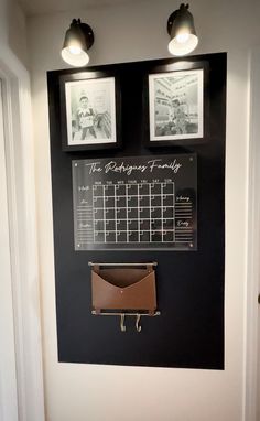 a wall mounted calendar with two pictures and a leather purse hanging on it's side