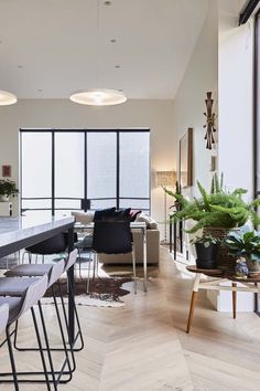 a living room filled with lots of furniture and tall windows next to a dining table