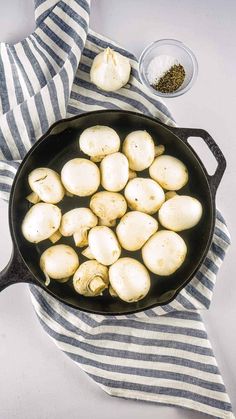 a cast iron skillet filled with mushrooms and seasoning next to a striped towel