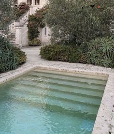 an outdoor swimming pool surrounded by greenery and trees with stairs leading up to it