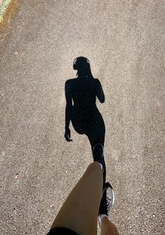 the shadow of a person's leg and foot as they walk down a street