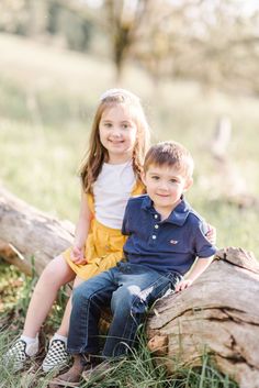 two children sitting on a log in the grass