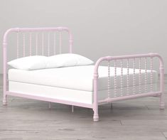 a pink metal bed frame with white pillows