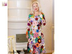 a woman standing in front of a white wall wearing a dress with flowers on it