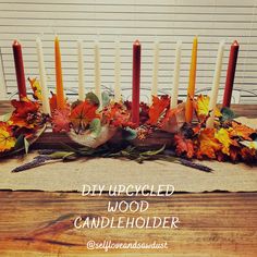 an arrangement of candles and fall leaves on a table with the words diy - dried wood candle holder