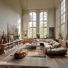 a living room filled with lots of furniture next to tall windows and large windows on the wall