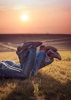 a person laying on the ground with their feet up in the air, wearing jeans and flip flops