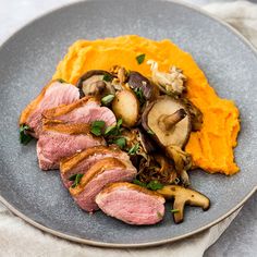 a plate with meat, mashed potatoes and mushrooms on it next to a fork