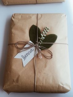 a wrapped present with a tag on it sitting on top of a table next to a piece of brown paper