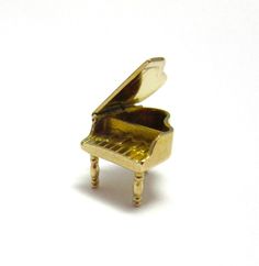 a miniature gold piano sitting on top of a table next to a white wall and floor