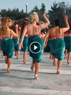 several women in green skirts are walking down the street