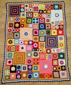 a crocheted blanket with squares and flowers on the bottom is laying on a wooden floor