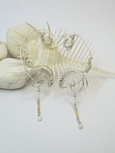 "Average delivery terms USA, France, Ireland - 3-4 weeks Australia, Canada - 4-6 weeks Netherlands, Spain - 2-3 weeks A pair of ear cuffs made of silver plated copper wire white and golden glass beads with delicate danglings. The length of the dangles is 1 1/3\" (3.4 cm). These earrings are covered by metal protecting lacquer. No piercing needed, they are worn behind the ear. Another metal (copper, brass) or beads or length of the dangles are also possible if you prefer to make some changes to t Handmade Adjustable Sterling Silver Body Jewelry, Elegant Handmade Sterling Silver Body Jewelry, Elegant Handmade Silver Body Jewelry, Elegant Handmade Body Jewelry As Gift, Elegant Handmade Body Jewelry For Gift, Unique Adjustable Pierced Ear Climbers, Unique Adjustable Nickel-free Ear Climbers, Adjustable Unique Ear Cuff, Adjustable Unique Style Ear Climbers