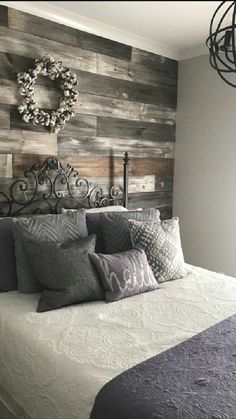 a bed with pillows and blankets on top of it in front of a wooden wall