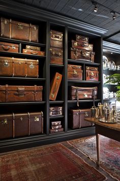 a room filled with lots of brown suitcases on shelves next to a table and rug