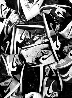 black and white photograph of many pairs of nike shoes stacked on top of each other