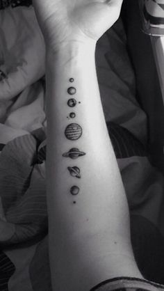 a person with a tattoo on their arm that has different planets and stars in it