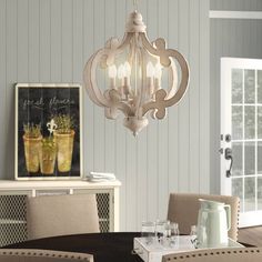 a chandelier hanging from the ceiling in a dining room with chairs and table