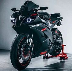 a black motorcycle parked in a garage next to a red tool stand with wheels on it