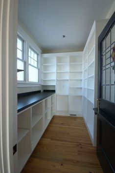 an empty room with white shelving and wood floors